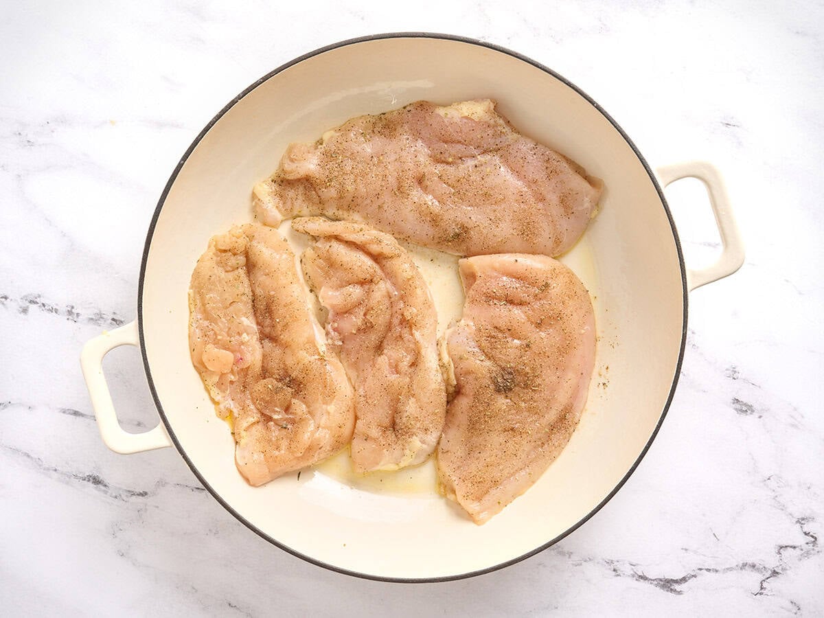 Chicken breast cutlets searing in a skillet.