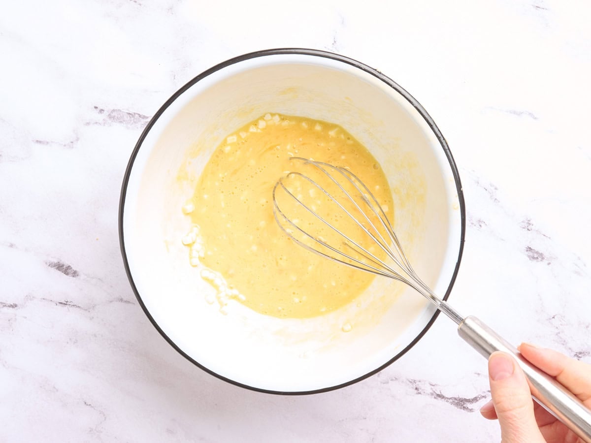 Cottage cheese being poured into beaten eggs.