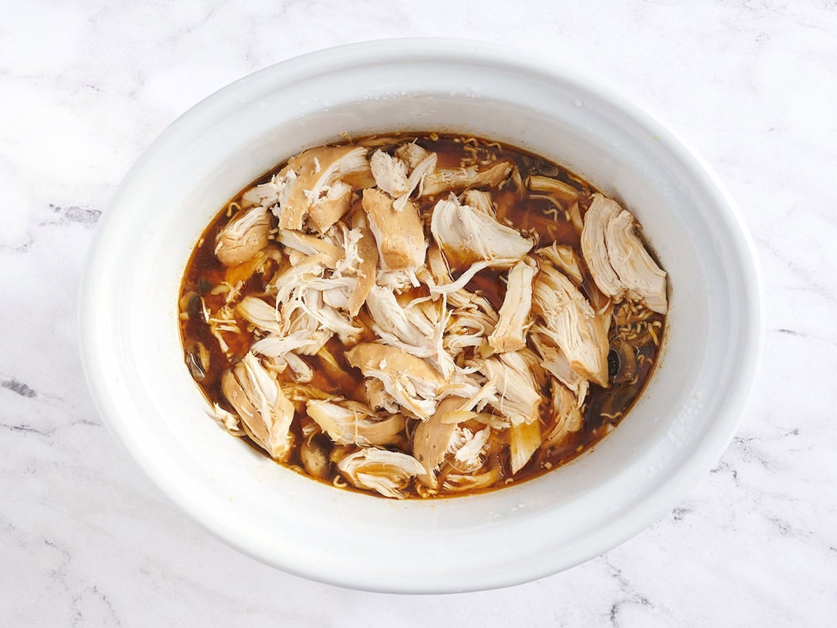 Shredded chicken added back to the broth for slow cooker ramen.