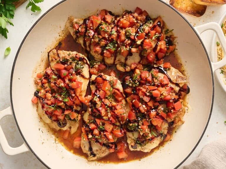 Overhead view of bruschetta chicken in a skillet topped with balsamic glaze.