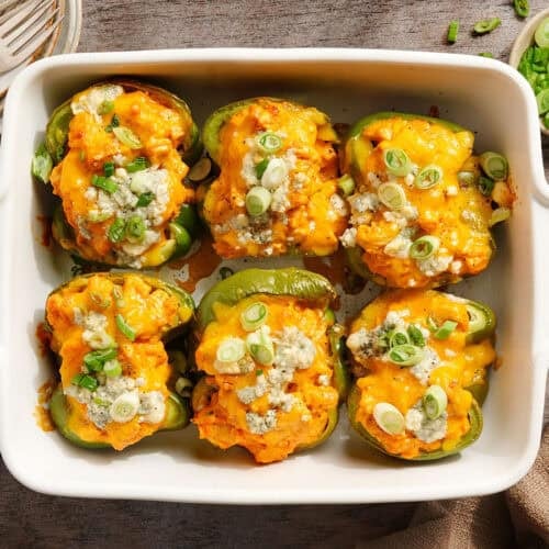Overhead view of creamy buffalo chicken stuffed peppers in a baking dish.