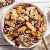 Overhead view of Casesar slaw with crispy chicken in a bowl with a fork.