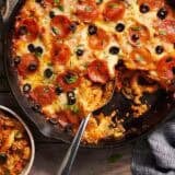 Overhead view of a skillet pizza casserole in a skillet next to a bowl.