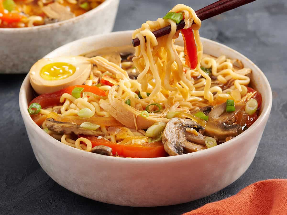 Side view of a bowl of slow cooked chicken and vegetables ramen.