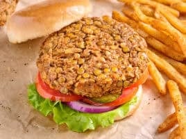 Overhead side view of a lentil burger in a hamburger bun, with salad and the top bun removed.