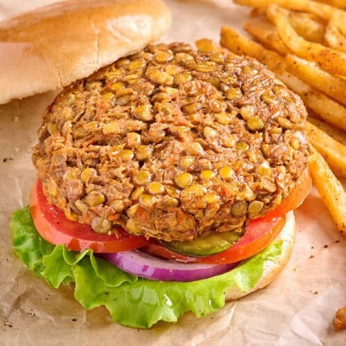 Overhead side view of a lentil burger in a hamburger bun, with salad and the top bun removed.