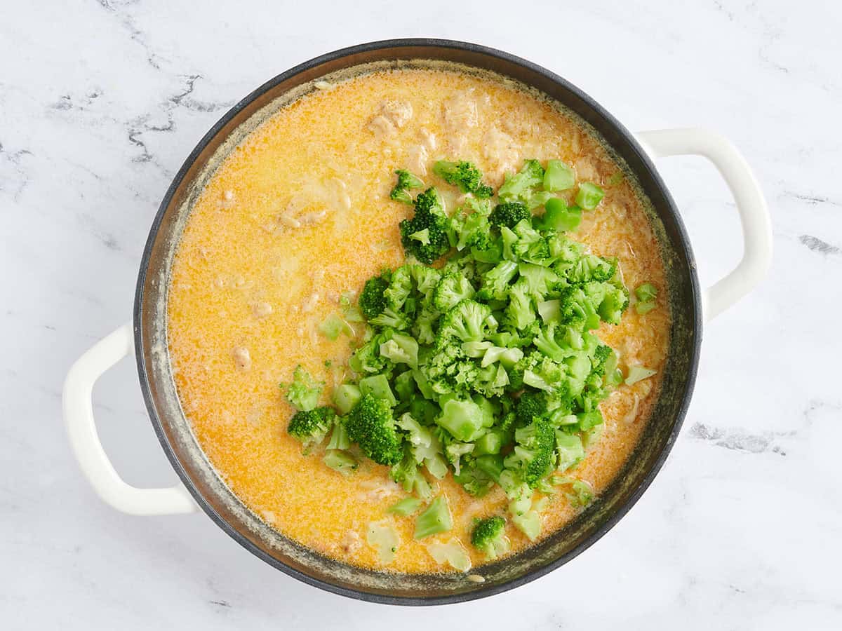 Frozen chopped broccoli added to a skillet.