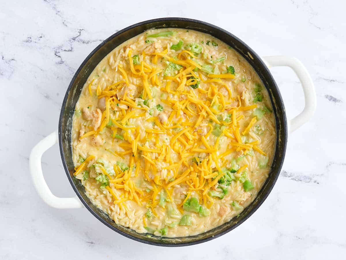 Cheddar cheese sprinkled over a skillet of chicken broccoli casserole.