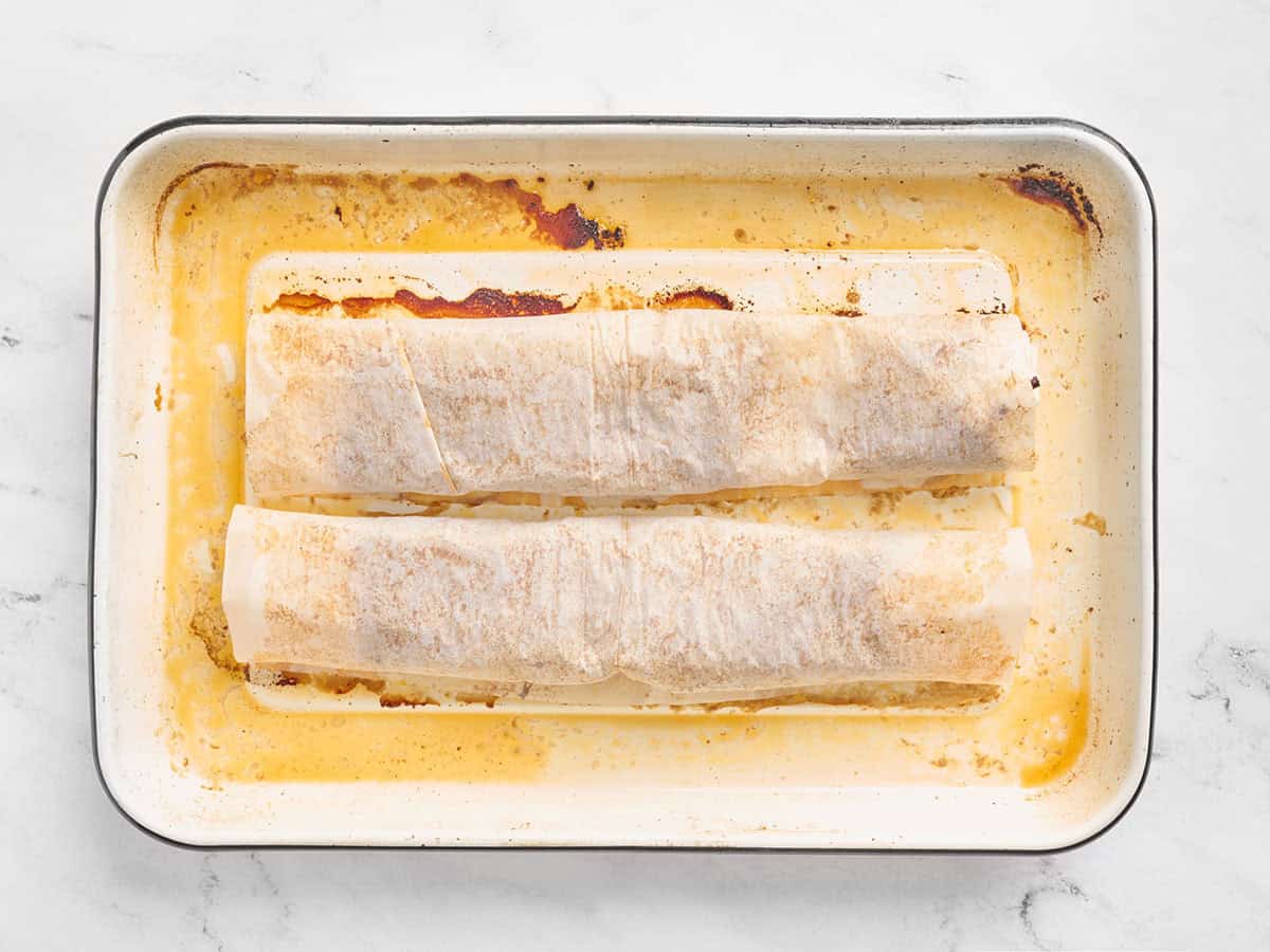 Cooked ground beef wrapped in a parchment on a sheet pan.
