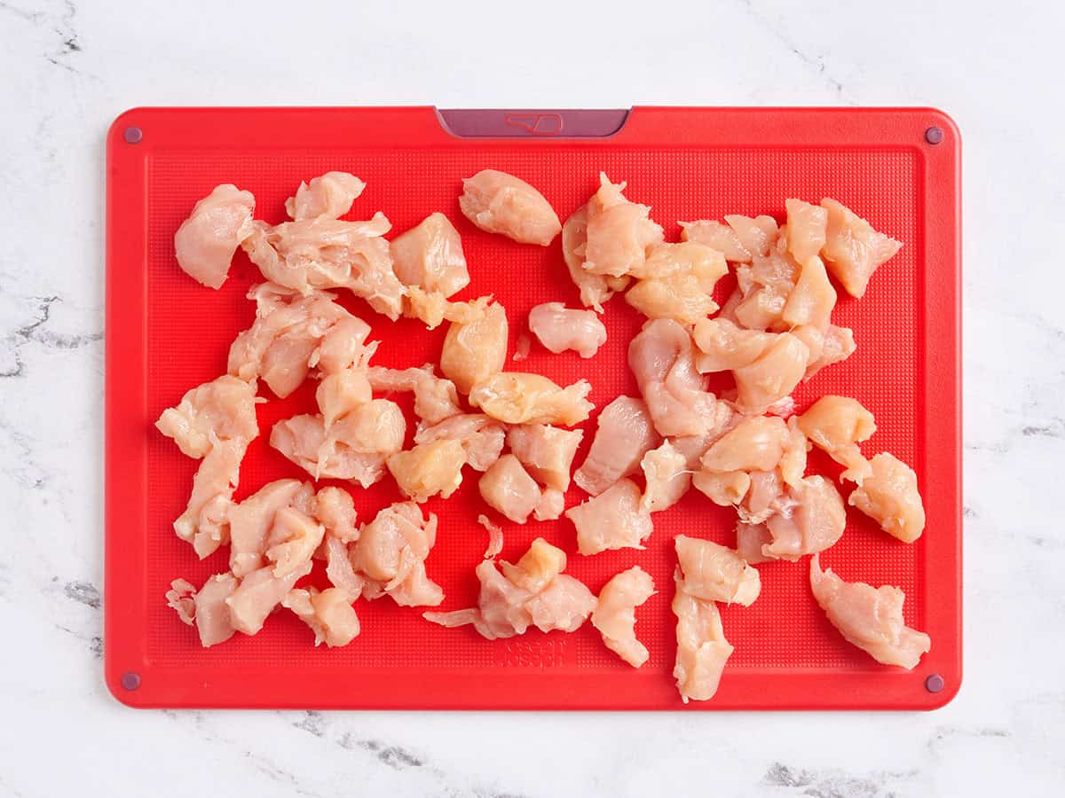 Chicken tenders cut into bitesized pieces on a cutting board.