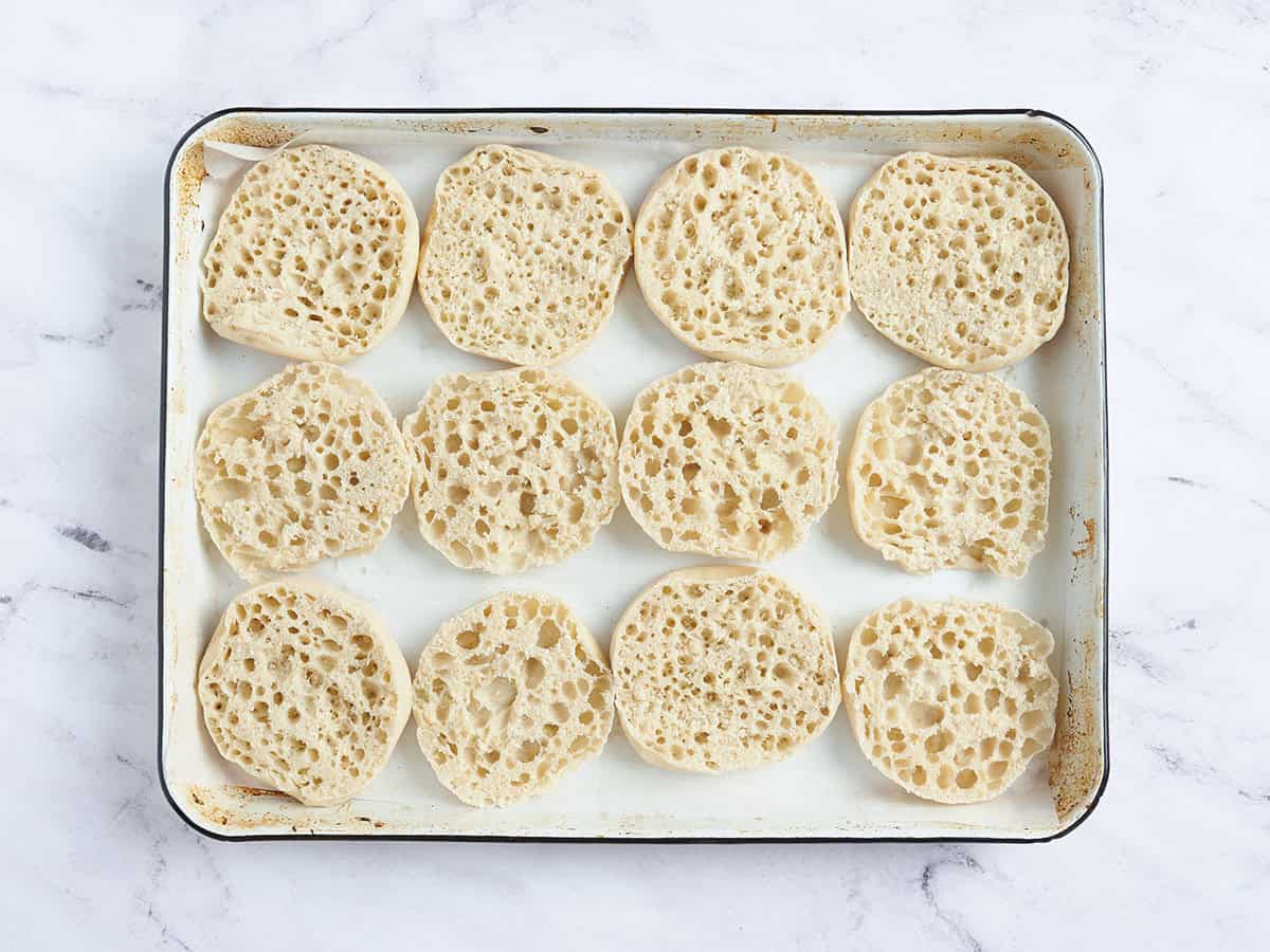 Sliced english muffins on a baking sheet.