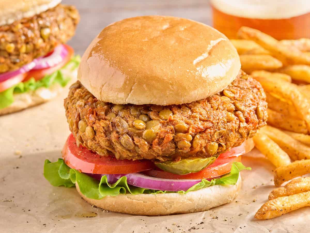 Side view of a homemade lentil burger in a hamburger bun with salad.