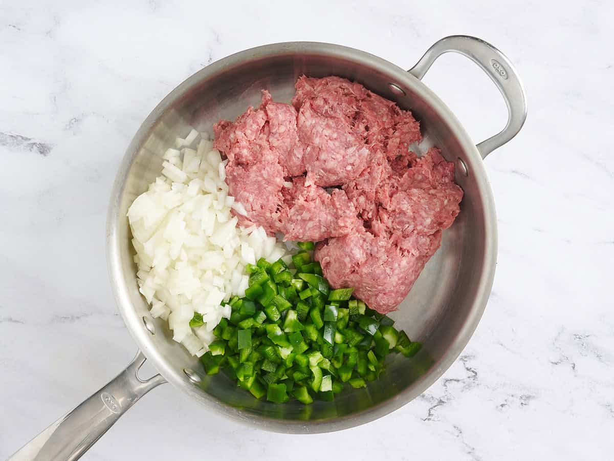 Ground beef, diced onion, and diced green bell pepper in a skillet.