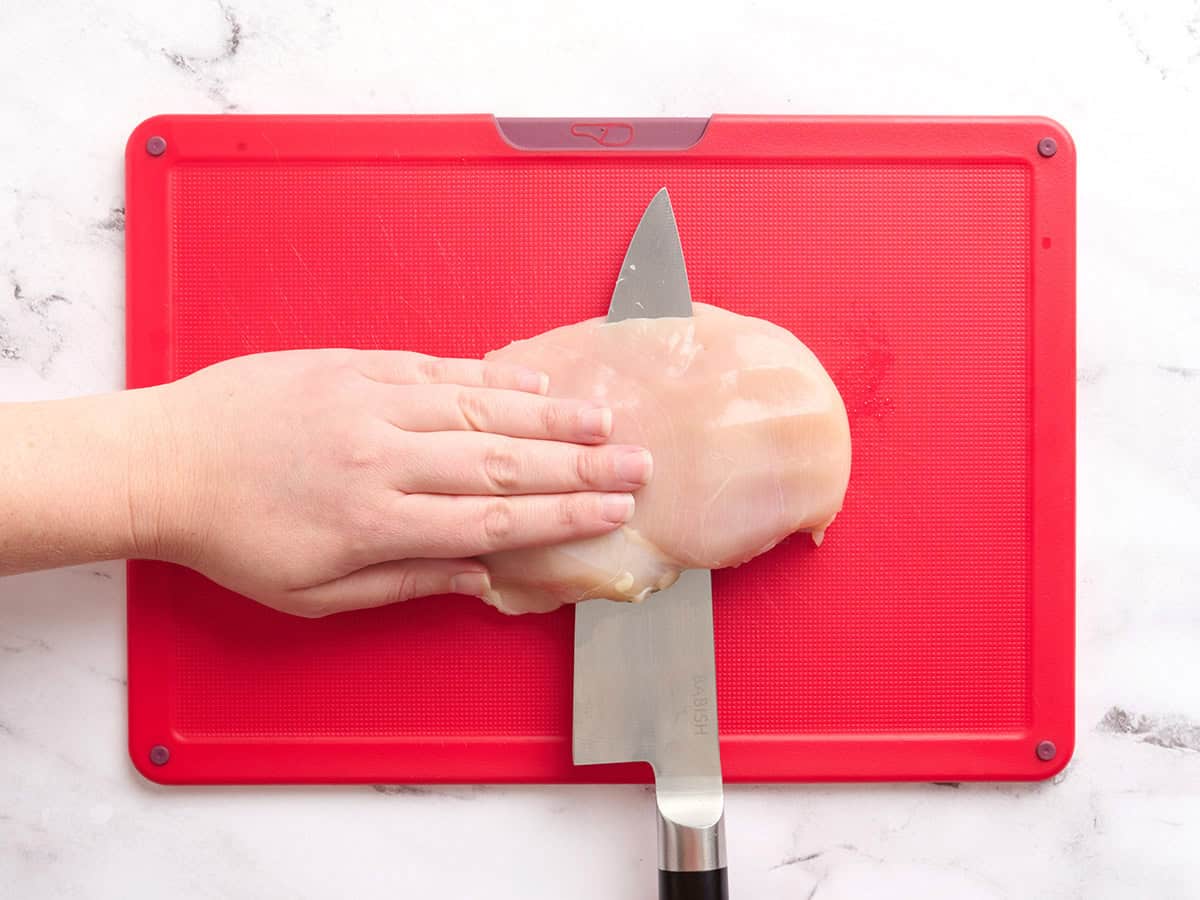 A chicken breast being sliced in half horizontally.