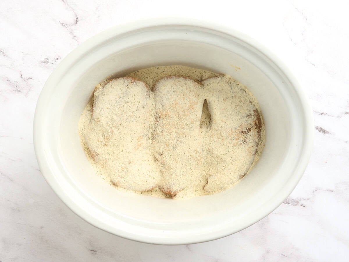 Chicken breasts in a crockpot with seasonings.