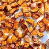 Overhead view roasted sweet potatoes with a metal spatula scooping some up.