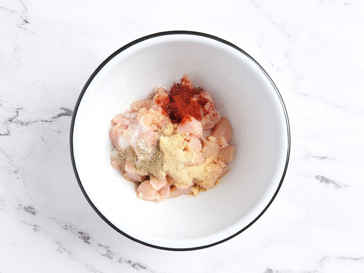 Chopped chicken tenders in a mixing bowl with seasonings.