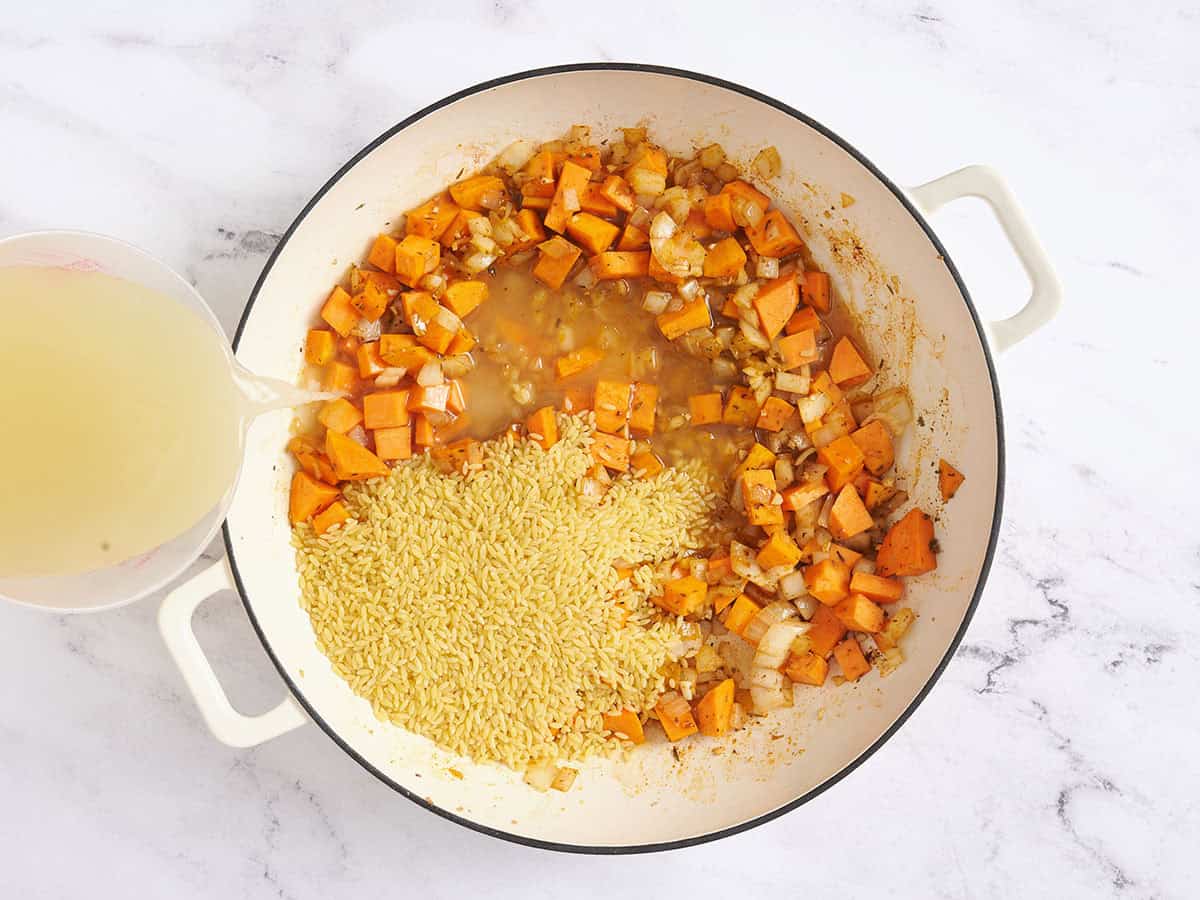 Broth being poured into a skillet of sweet potatoes.