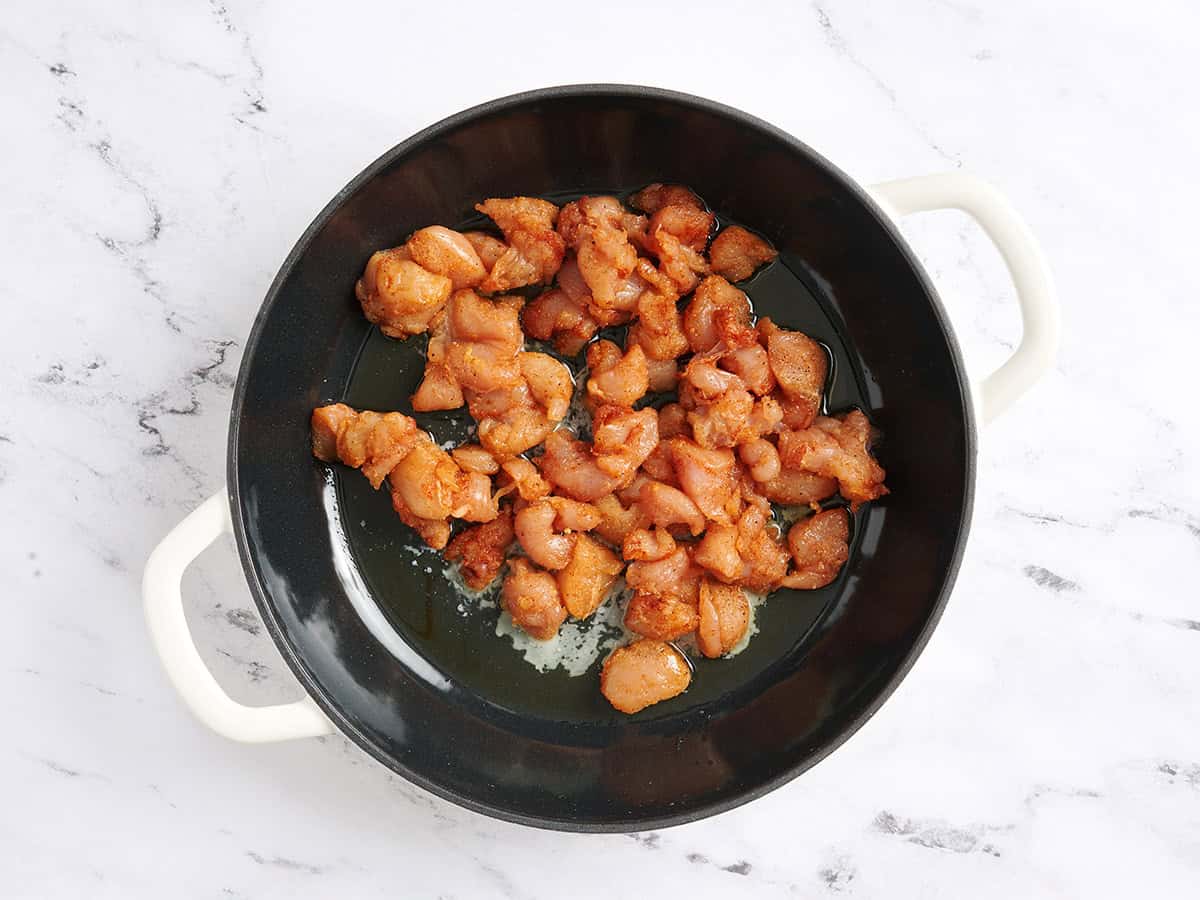 Chicken chunks in a skillet.