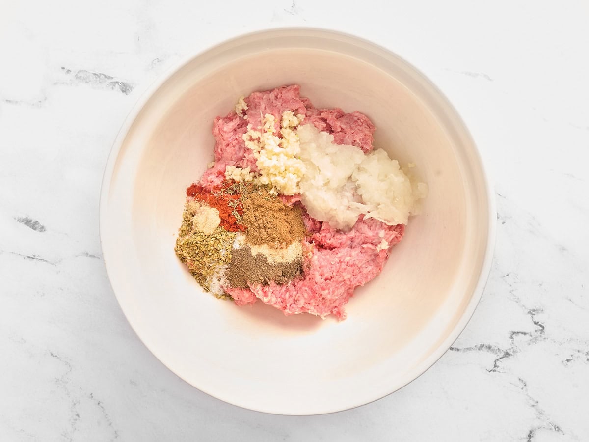 Ground beef, minced onion, seasonings, and minced garlic in a mixing bowl.