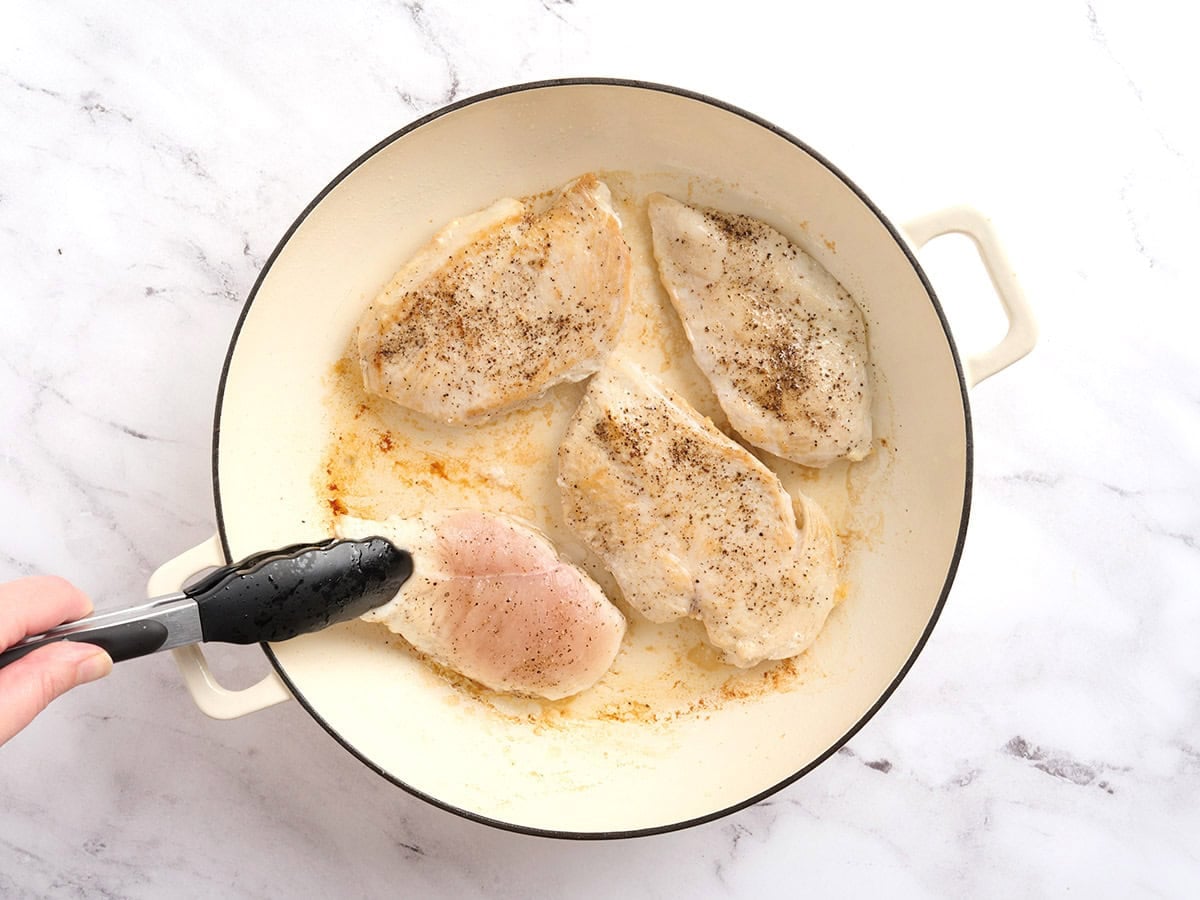Chicken filets searing in a skillet.