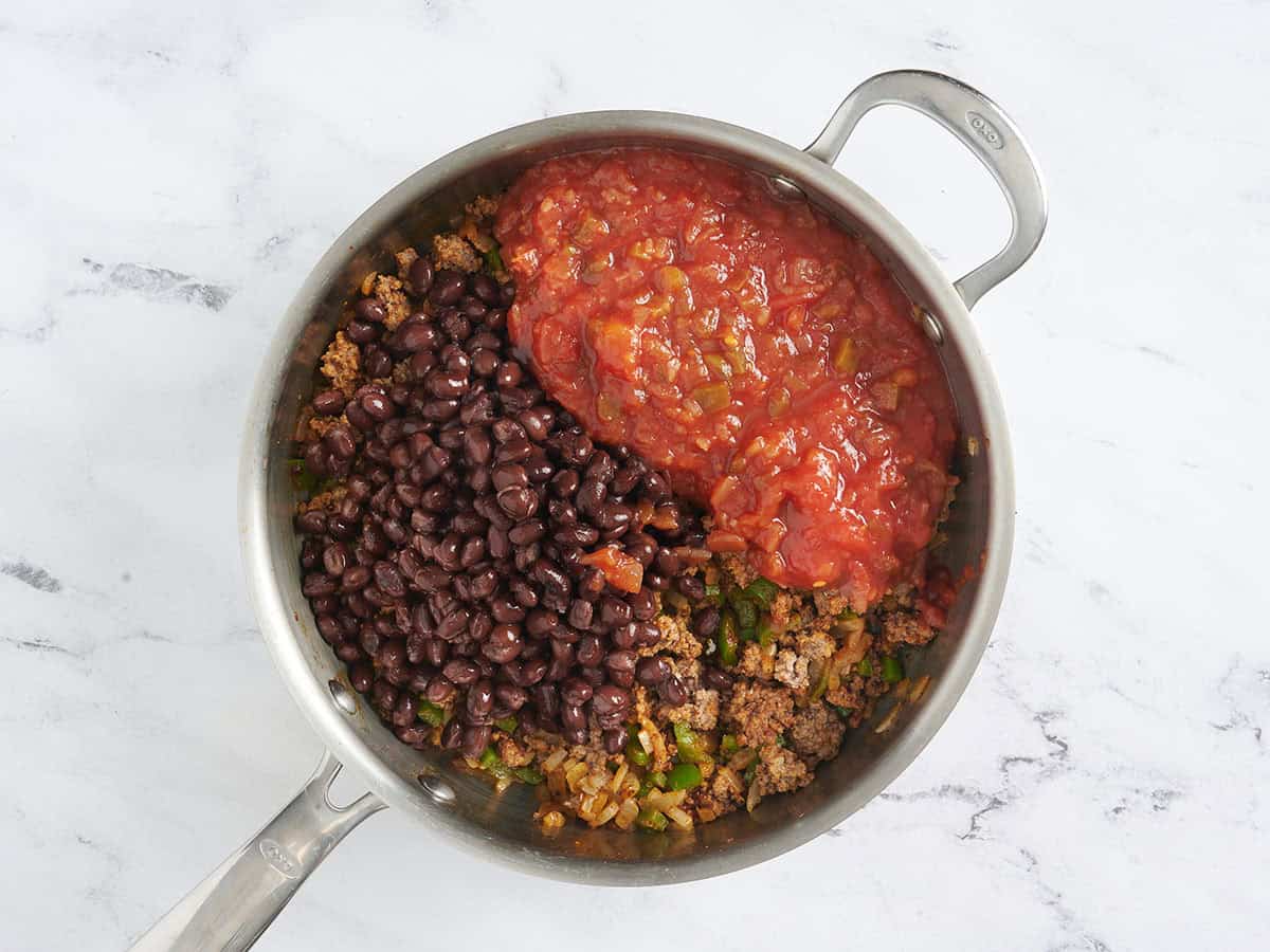 Black beans and salsa added to a skillet of brown ground beef.