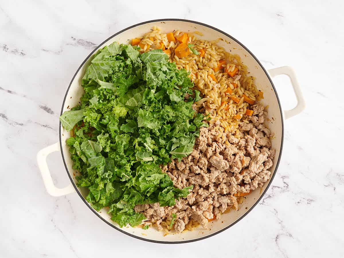 Kale and cooked ground turkey added to a skillet with sweet potatoes.