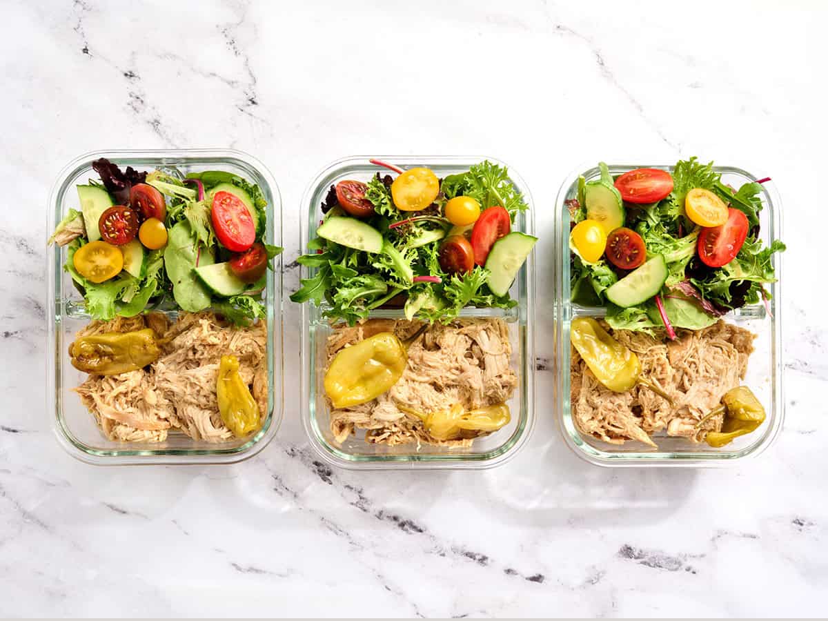 Overhead view Mississippi chicken on three meal prep containers with a green salad.