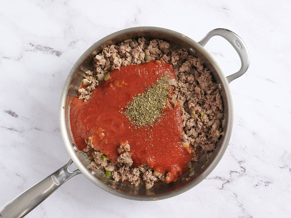 Marinara sauce added to a skillet with italian seasoning and browned ground meat.