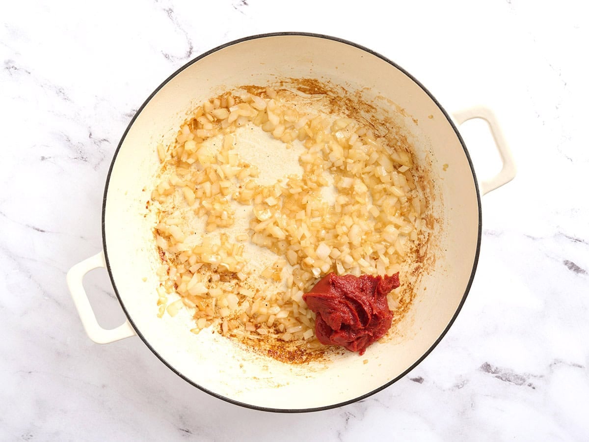 Tomato paste added to a skillet on sauteed onions and garlic.