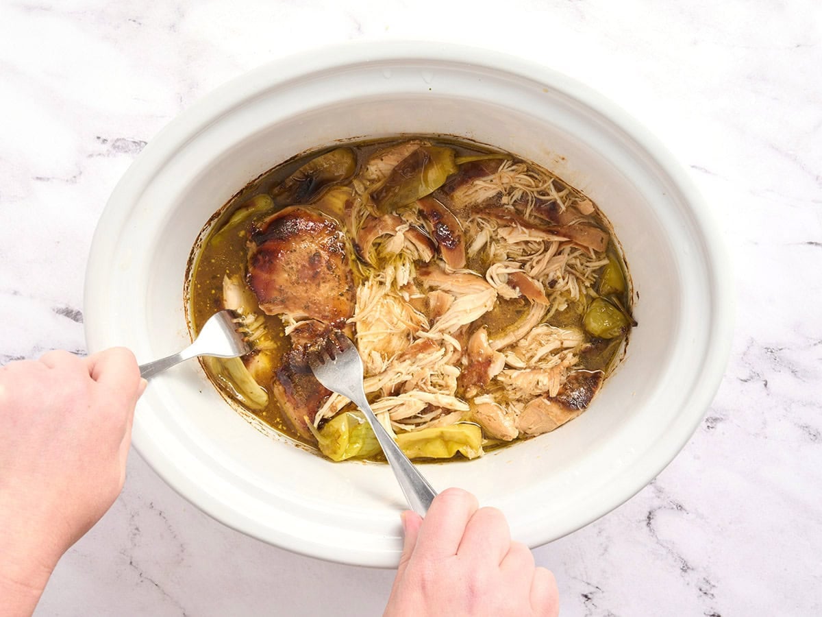 Forks shredded Mississippi chicken in a crockpot.