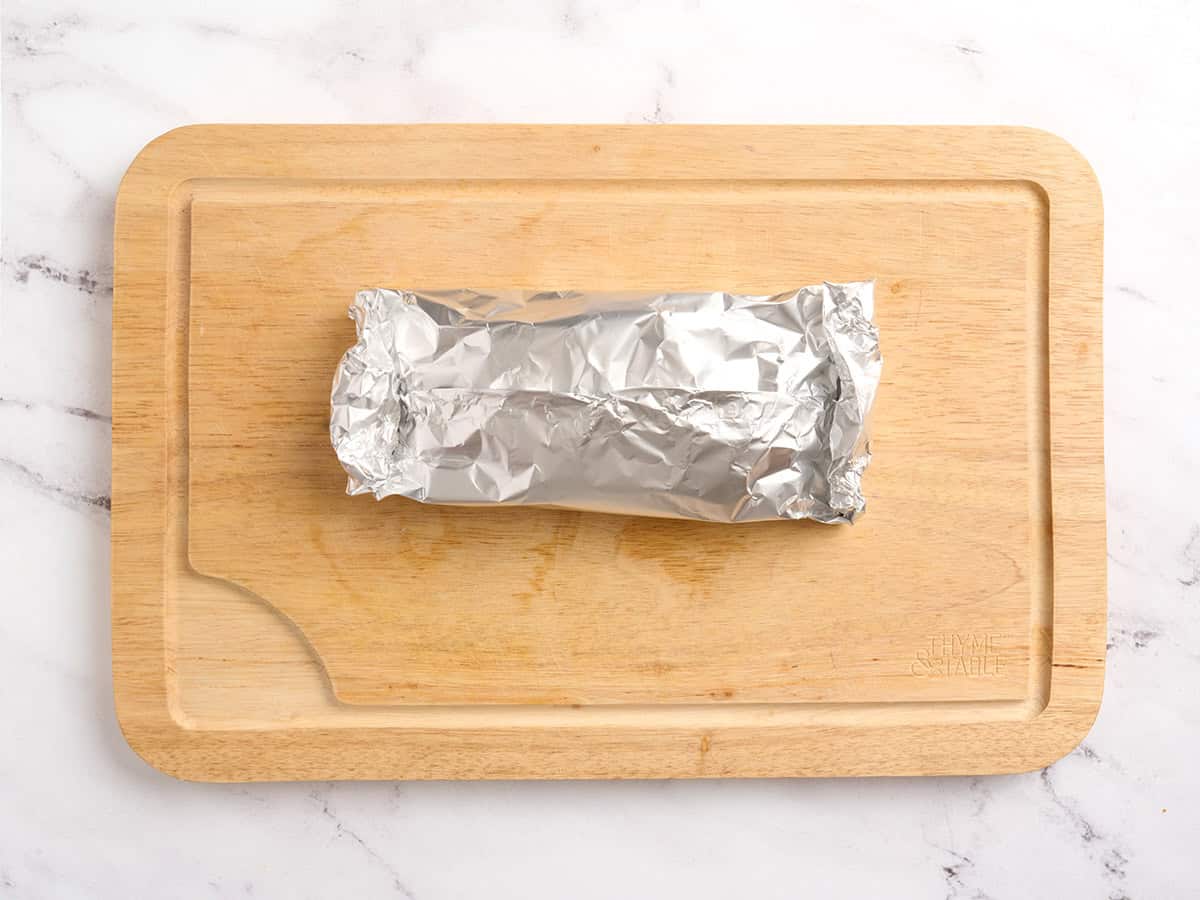 A folded foil packet on a wooden cutting board.