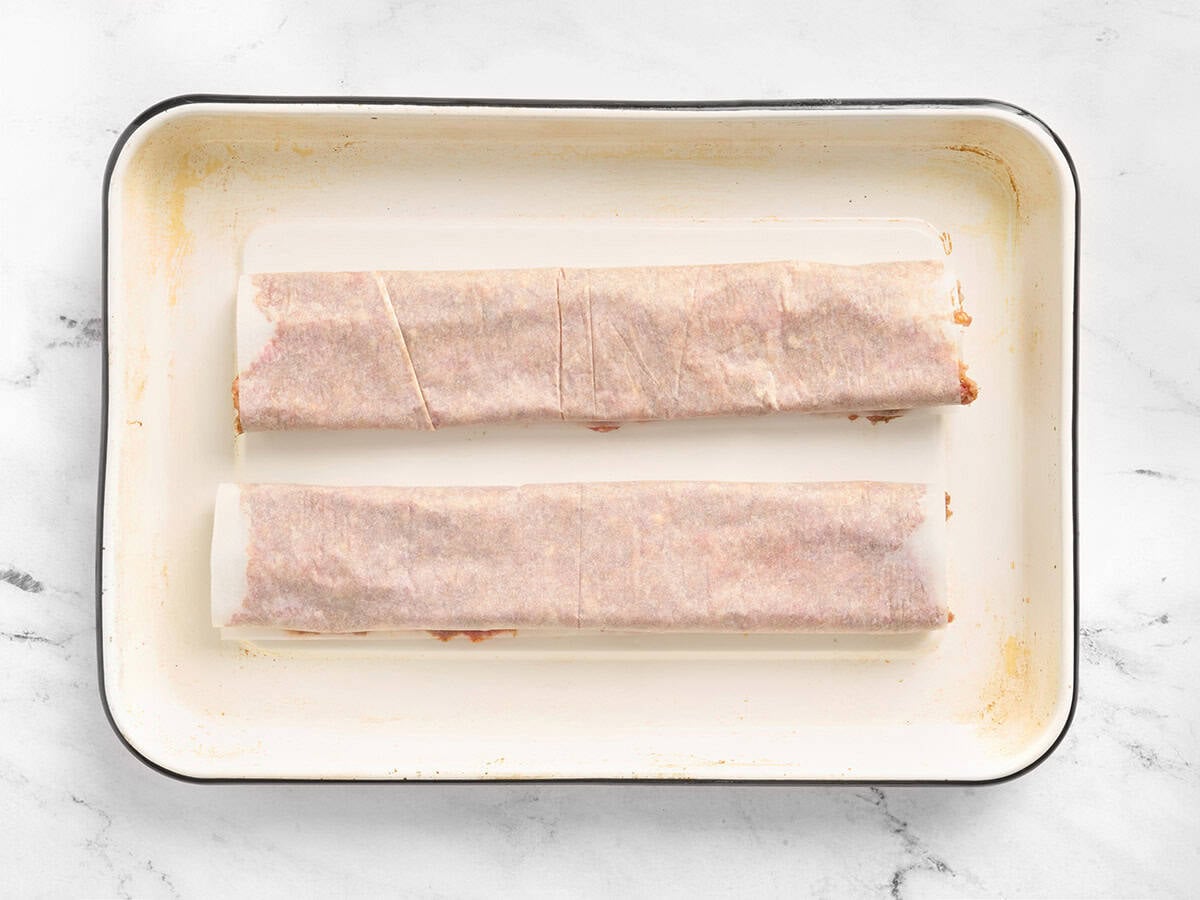 Meat rolled in parchment on a sheet pan.