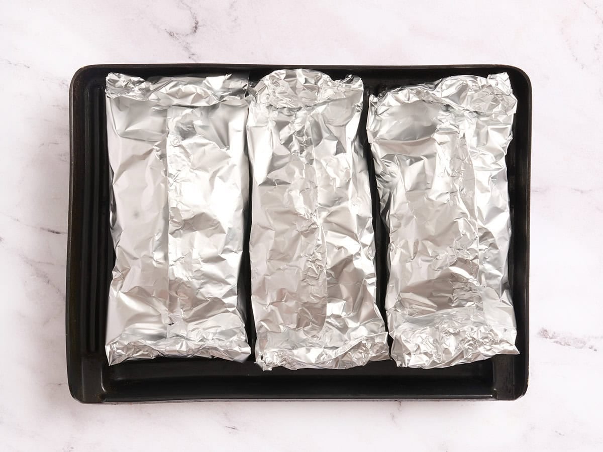 Three foil packets on a grill.