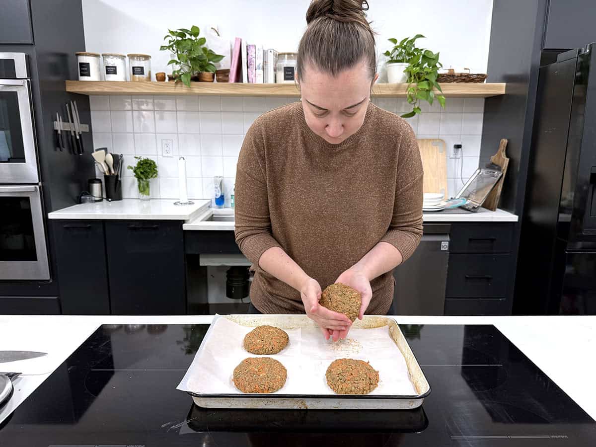 A woman shaping lentil burgers in a kitchen.