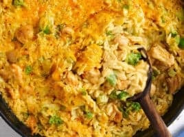 Overhead close up view of a chicken broccoli casserole with a wooden spoon.