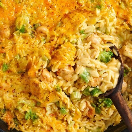 Overhead close up view of a chicken broccoli casserole with a wooden spoon.