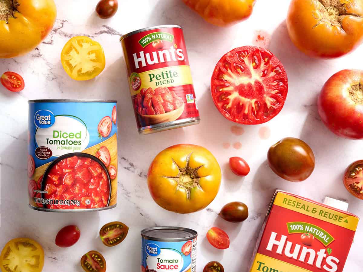 fresh tomatoes and cans of diced tomatoes laid out