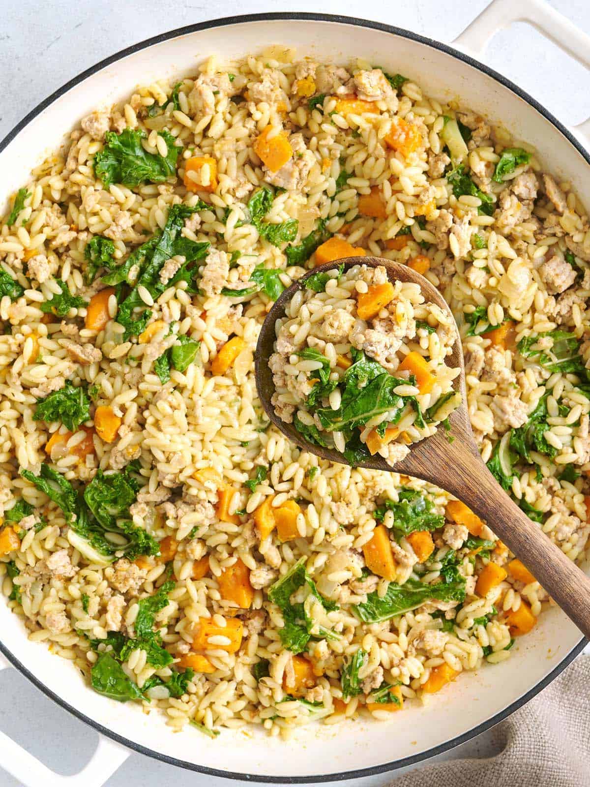 Overhead view of a sweet potato and ground turkey skillet with a wooden spoon.