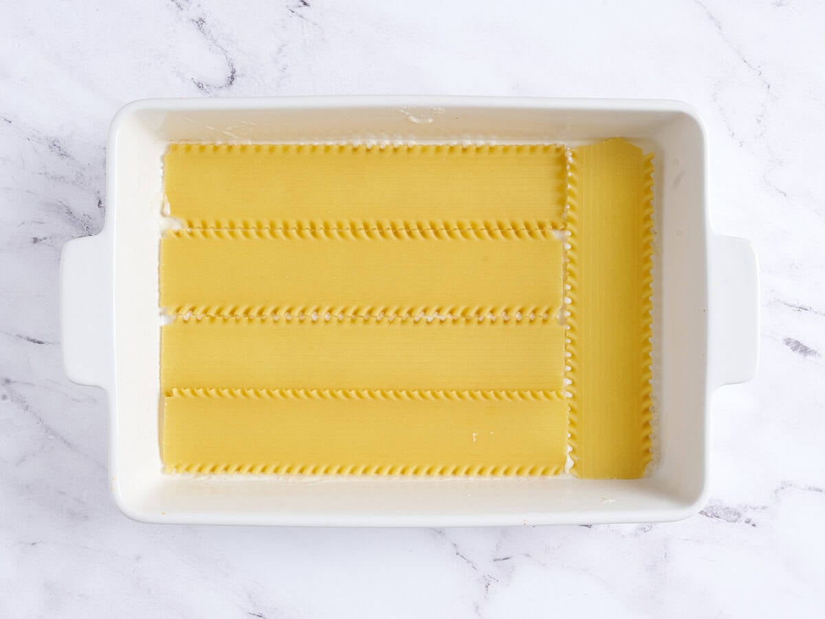 A layer of lasagna noodles added to a baking dish.