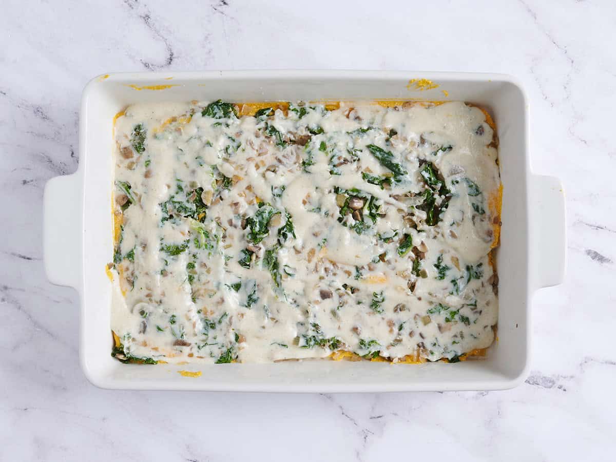 Another layer of bechamel sauce added on top of the mushroom and kale filling for a butternut squash lasagna.