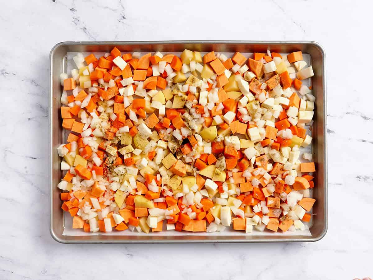 Diced root vegetables on a sheet pan topped with seasonings.
