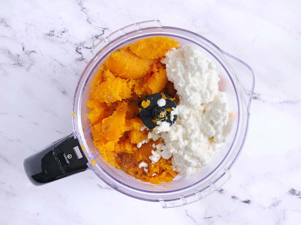Roasted butternut squash in a food processor with cottage cheese.