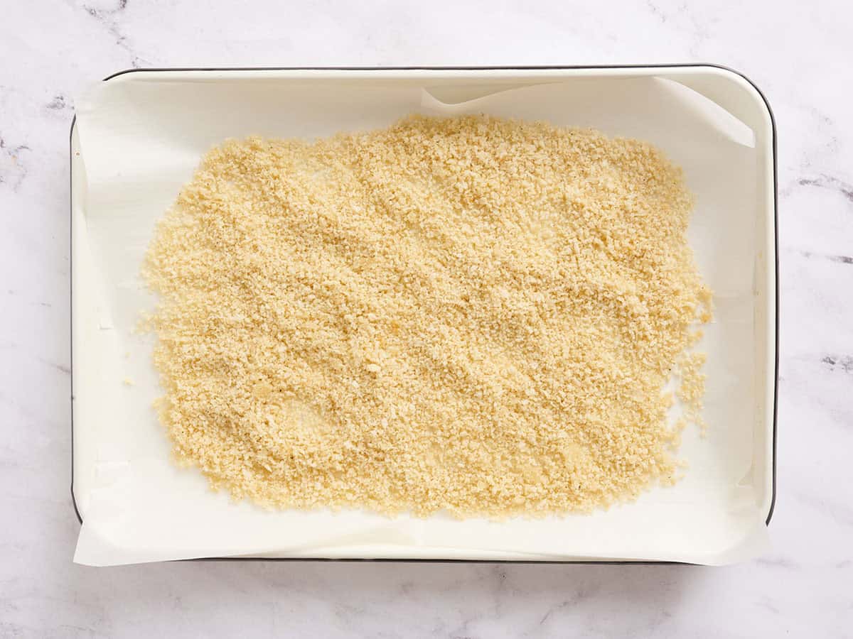 Seasoned breadcrumbs on a baking sheet before toasting.