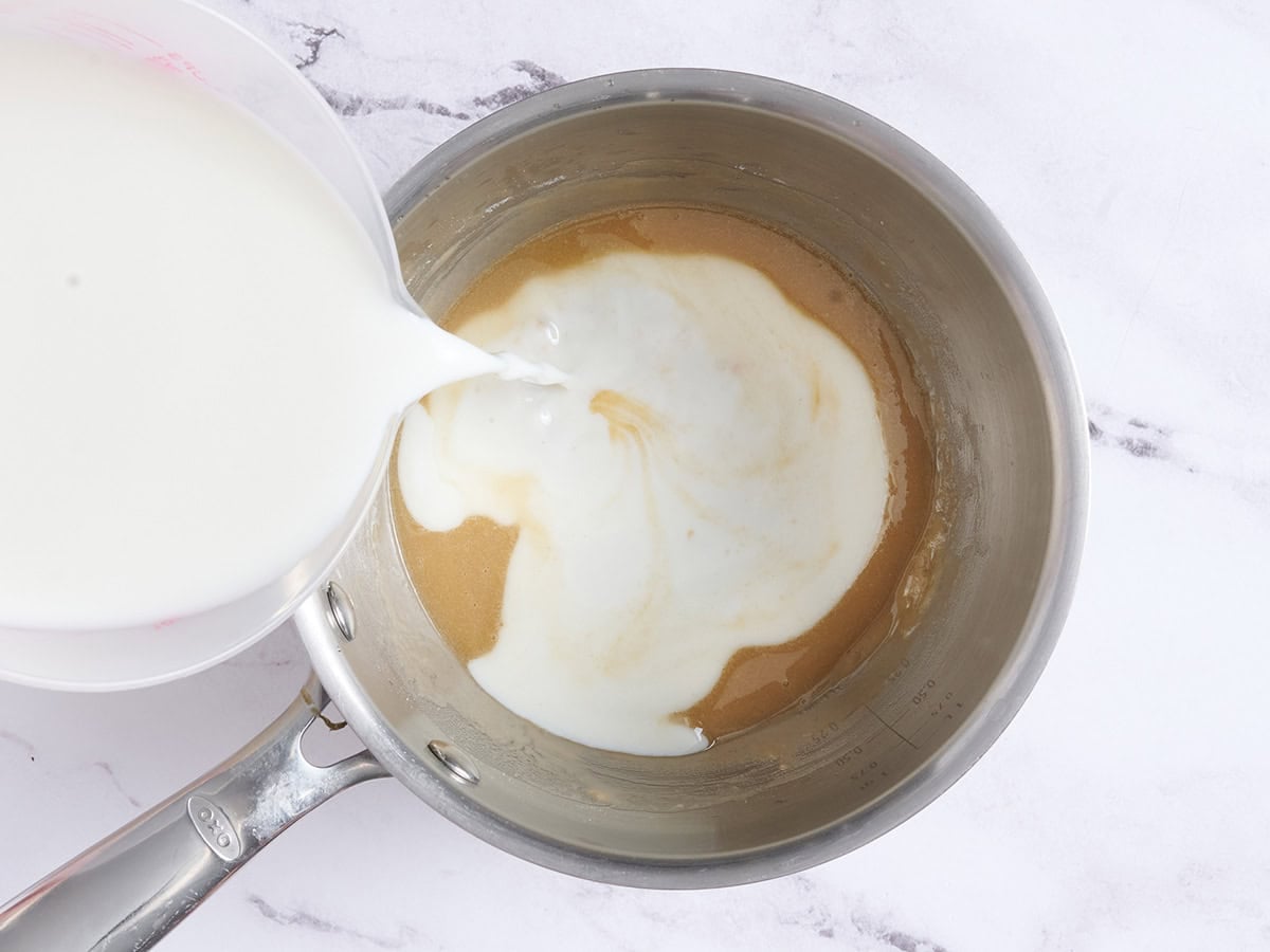 Milk added to a brown butter roux in a saucepan.
