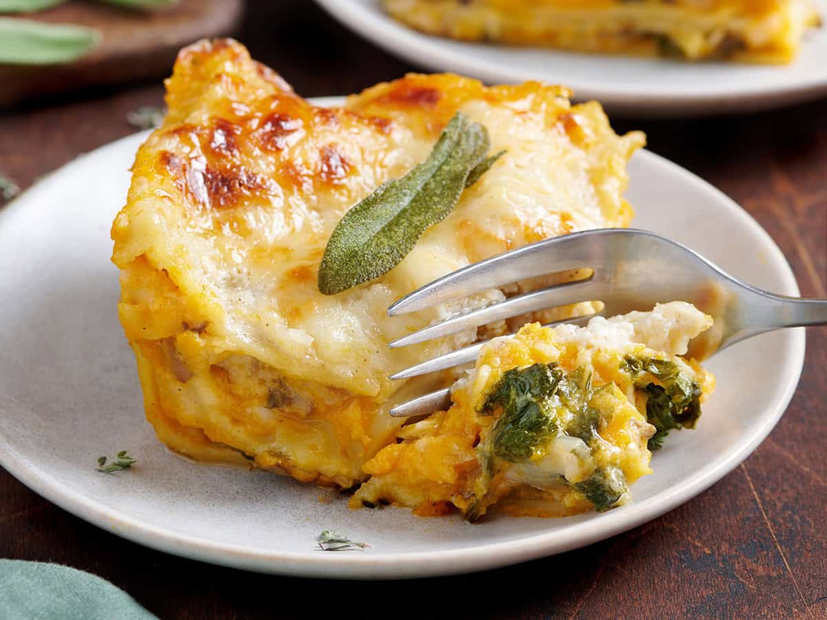 Side view of a slice of butternut squash lasagna with a fork taking some.