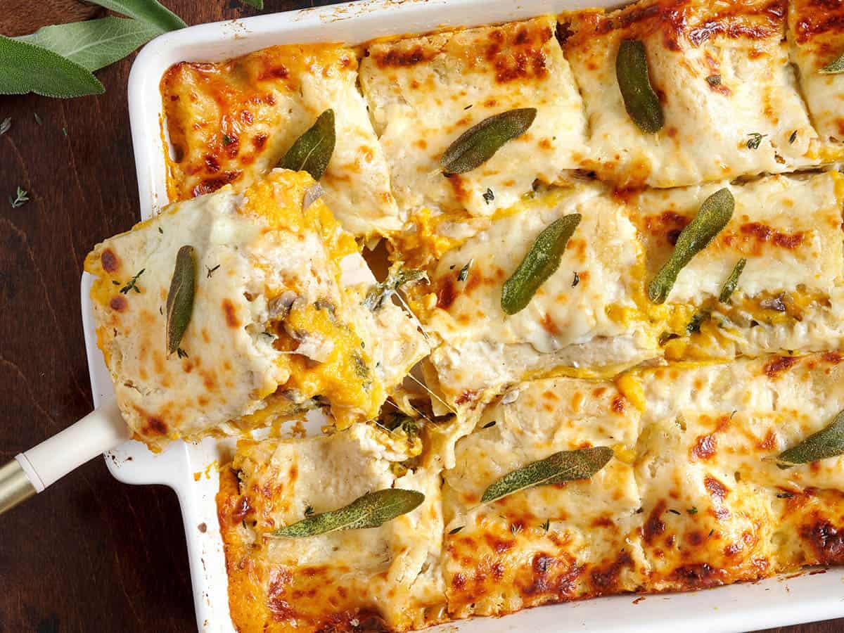Overhead view of a slice of butternut squash lasagna being taken from the baking dish.