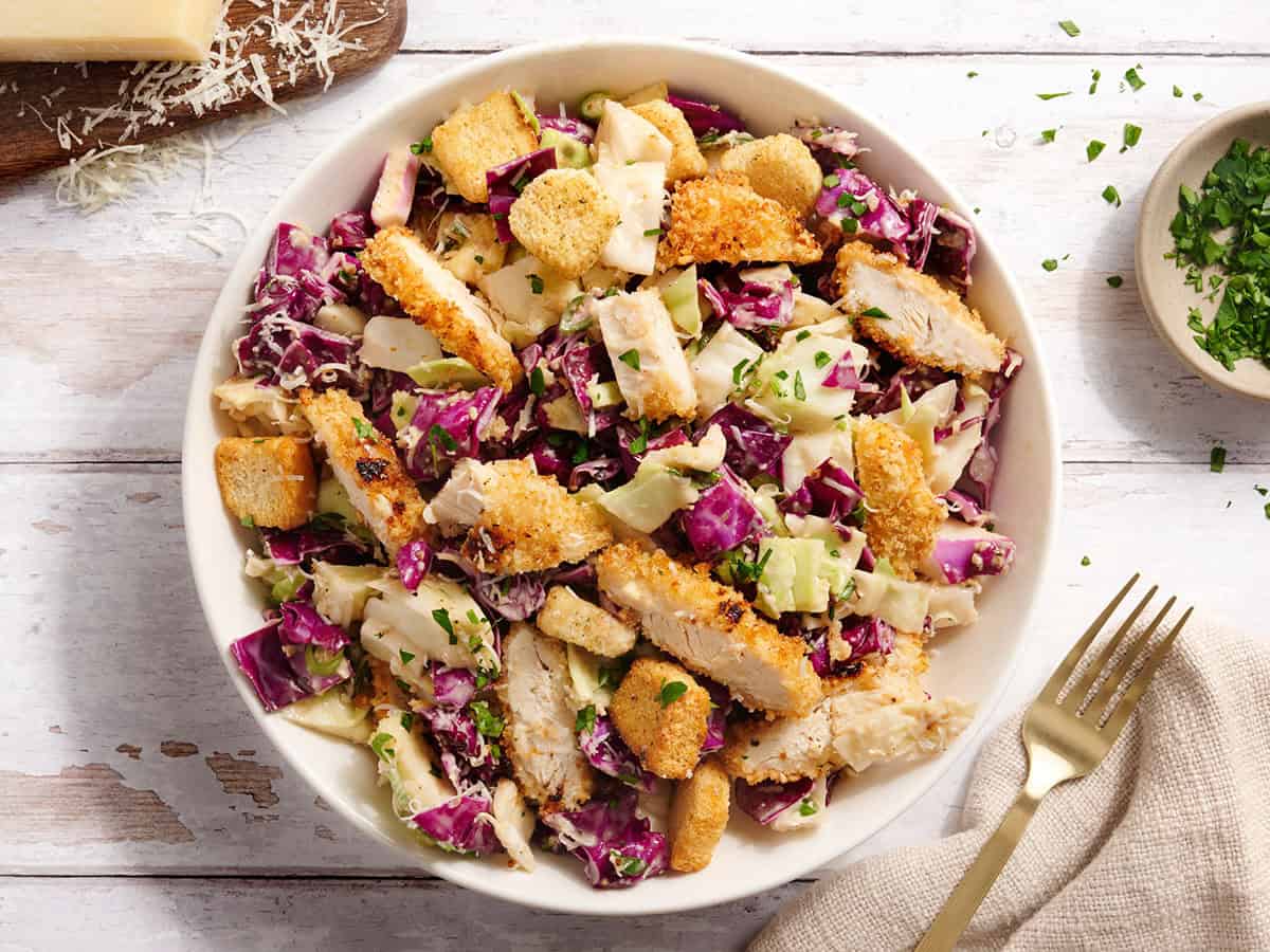 Overhead view of a cabbage caesar chicken salad in a bowl.